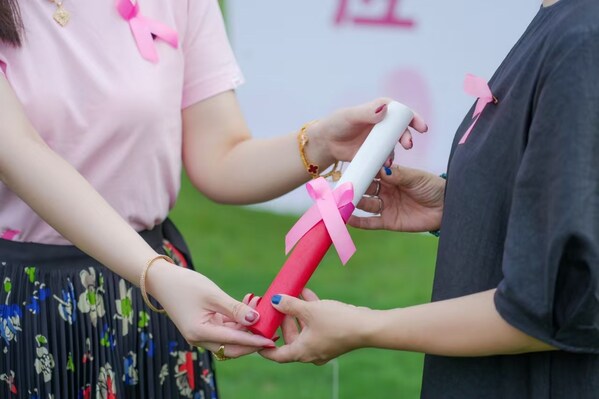 復(fù)旦學(xué)子代表把象征粉紅力量的粉色接力棒傳遞給社會(huì)受助者